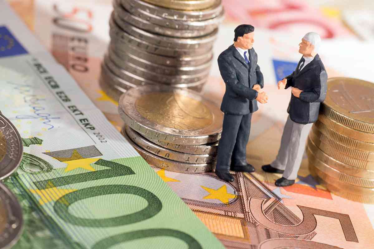 Zwei kleine Figuren stehend auf Geldscheine umringt von Münzen 